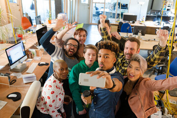 Team taking group selfie with smartphone in office