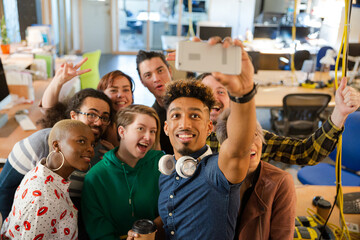 Obraz premium Team taking group selfie with smartphone in office