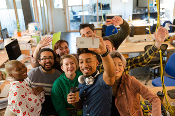 Team taking group selfie with smartphone in office