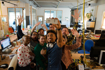 Team taking group selfie with smartphone in office