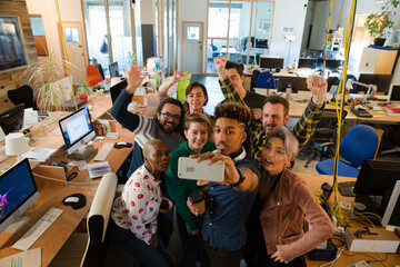 Team taking group selfie with smartphone in office