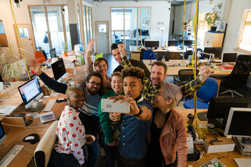 Fototapeta na wymiar Team talking group selfie with smartphone in office