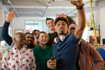 Obraz premium Team taking group selfie with smartphone in office