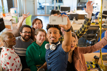Team taking group selfie with smartphone in office