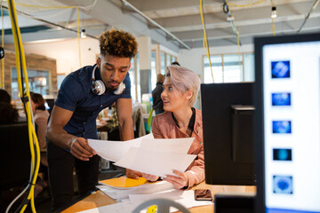 Man and woman discussing paperwork at desk