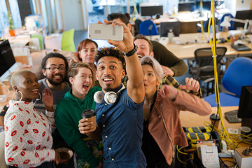 Obraz premium Team taking group selfie with smartphone in office