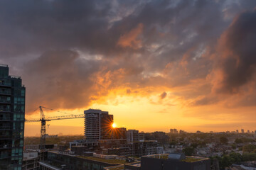 Colorful sunset illuminating storm clouds over high rise apartment buildings and a crane in Ontario...