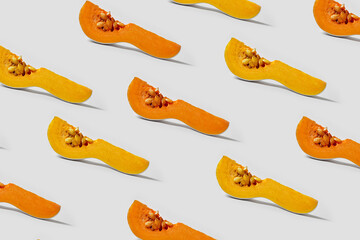 Stylish poster with a pattern of white pumpkin slices with yellow and orange flesh with seeds on a white background