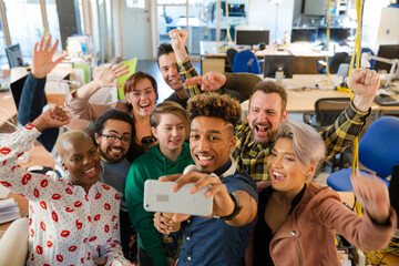 Team talking group selfie with smartphone in office