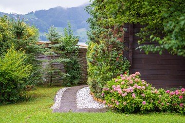 Courtyard with flowers, tree and lawn next to the lake on a rainy summer day in Austria