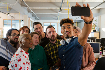 Team talking group selfie with smartphone in office