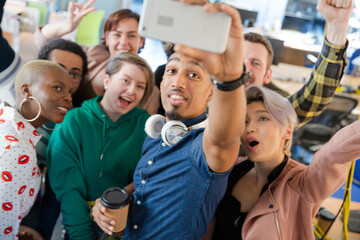 Team taking group selfie with smartphone in office