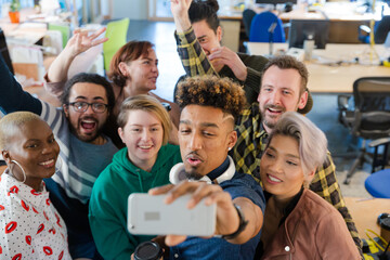 Team taking group selfie with smartphone in office