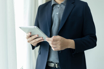 Business partners concept a young businessman wearing navy suit jacket looking on the tablet screen checking an email inbox