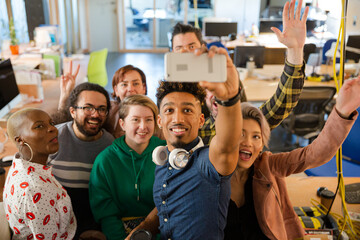Team taking group selfie with smartphone in office