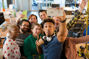 Team taking group selfie with smartphone in office