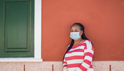 Fototapeta na wymiar Senior african american woman in the city wearing safety face mask for coronavirus outbreak