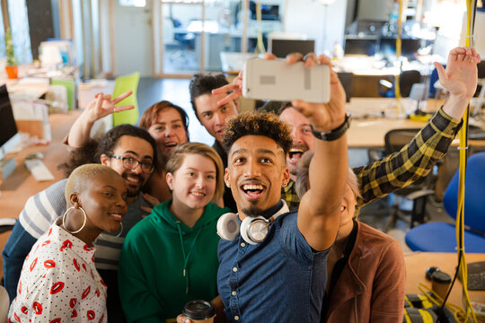 Team taking group selfie with smartphone in office