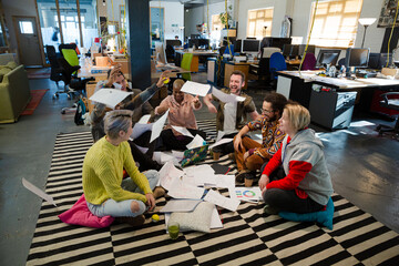Fototapeta na wymiar Team sitting on floor, discussing paperwork
