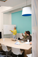 Businesswoman at whiteboard leading conference room meeting