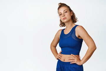 Portrait of sportswoman workout, standing confident in sportsbra with hands on waist, looking...