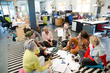 Team sitting on floor, discussing paperwork