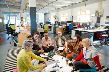 Team sitting on floor, discussing paperwork