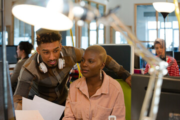 Man and woman discussing paperwork at computer
