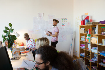 Young man hanging work plan schedule on wall in office