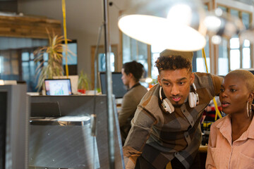 Man and woman discussing paperwork at computer