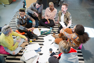 Fototapeta na wymiar Team sitting on floor, discussing paperwork