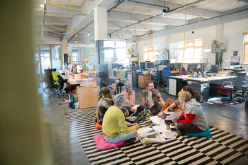 Team sitting on floor, discussing paperwork