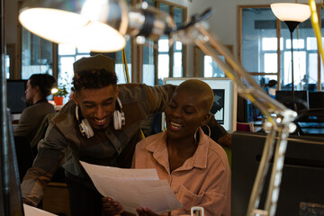Man and woman discussing paperwork at computer