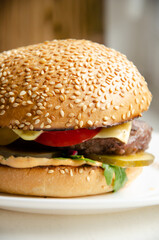 Juicy burger with baked bun, melted cheese, meat patties and vegetables. Unhealthy food concept. Delicious fast food. Serving hamburger.