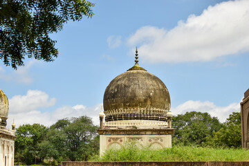 Obraz premium Antique Islamic Architectural Art Pointed Arches Seven Tombs Dome and Blue Sky Green Trees