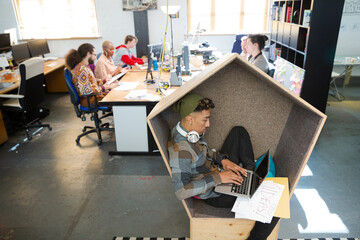 Young man working at laptop in modern armchair