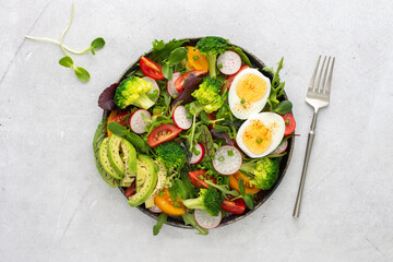 Delicious light breakfast, salad with tomatoes and radishes, avocado and boiled eggs, top view