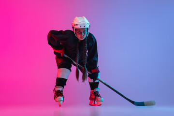 Portrait of child girl - professional hockey player isolated over gradient pink purple background