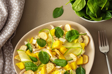 Plate with salad and fork close-up on a brown background, salad of cucumber and chicken breast,...