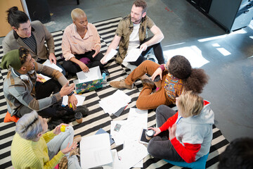 Team sitting on office floor, discussing paperwork