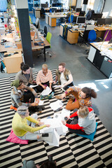 Team sitting on office floor, discussing paperwork