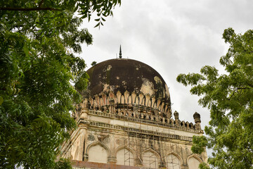 Obraz premium Antique Islamic Architectural Art Pointed Arches Seven Tombs Dome and Blue Sky Green Trees