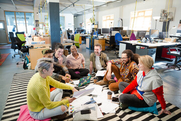 Team sitting on floor, discussing paperwork