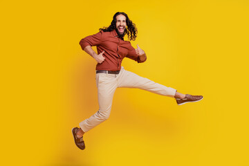 Fototapeta na wymiar Portrait of funky positive guy jump raise thumb up open mouth on yellow background
