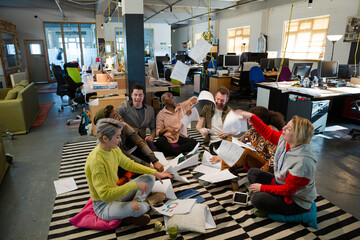 Team sitting on floor, discussing paperwork
