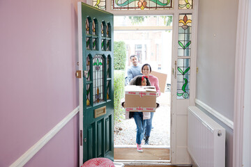 Happy family moving house, carrying cardboard boxes in corridor