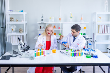 Fototapeta na wymiar Two scientists are working holding looking at test tube with sample in a chemistry lab scientist or young female and male researcher are doing investigations in Laboratory analysis background