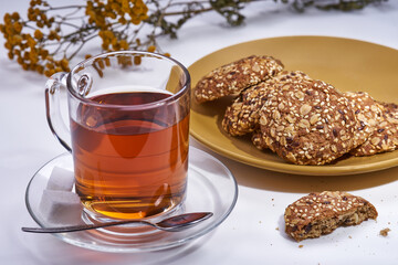 A cup of tea a plate with cookies yellow flowers on a white background