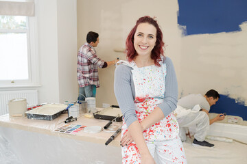 Portrait confident woman in overalls painting room with friends