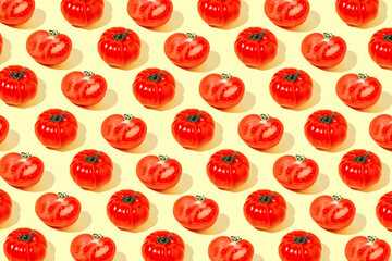 Creative pattern made of fresh raw red tomatos on pastel yellow background. Healthy food concept.